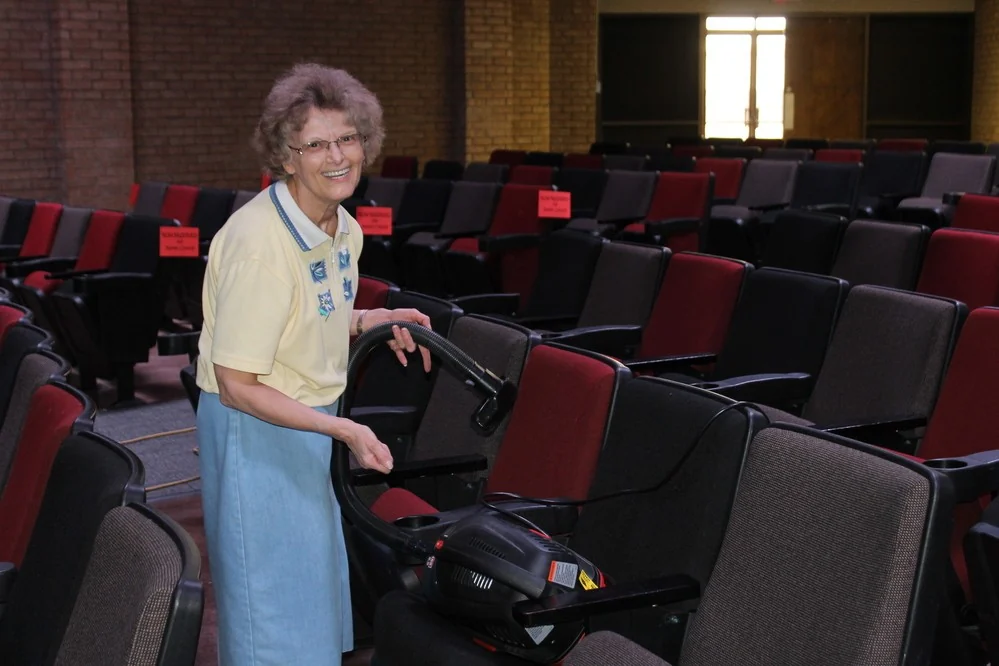 A smiling church member helping care for the sanctuary at Higher Plain